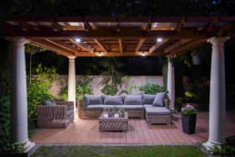 A cozy outdoor veranda with wicker sofas and pot plants